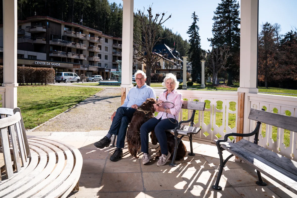 Rolf und Sally Zollinger in Vulpera mit ihren beiden Hunden am Standort des abgebrannten Grandhotels. Rolf und Sally Zollinger, Vulpera. Field Spaniels Holly and Phoebe. Grandhotel Waldhaus Vulpera. Kurpark Vulpera.
